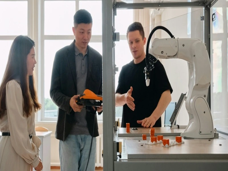 estudantes interagindo com aparelho robótico de indústria