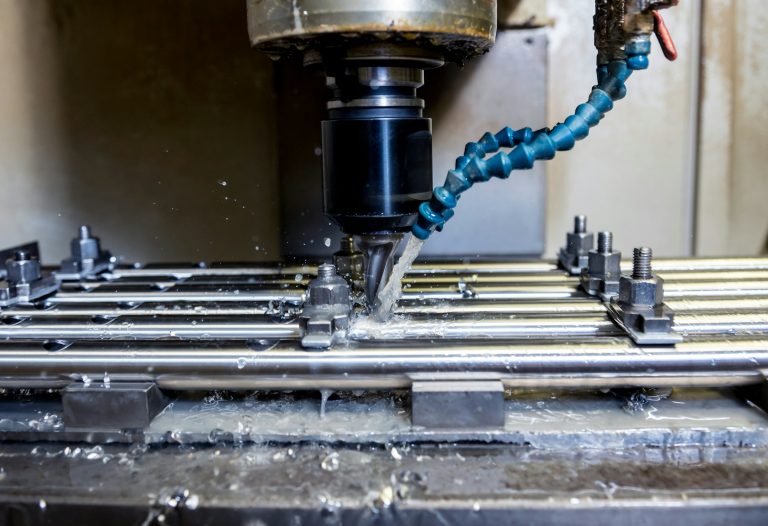 Imagem de uma máquina CNC em operação, mostrando o processo de usinagem de peças metálicas com fluído lubrificante, ideal para indústria e fabricação.