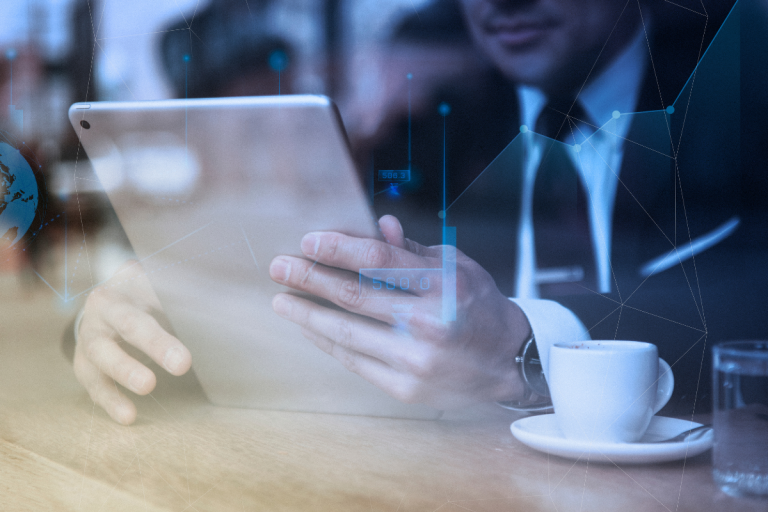 A imagem mostra um profissional de negócios (provavelmente um homem, dado o terno escuro) sentado em um ambiente que parece ser um café, escritório ou sala de reunião, enquanto interage com um tablet digital.