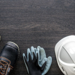 Esta imagem mostra itens de Equipamento de Proteção Individual (EPI) em uma superfície escura de madeira.