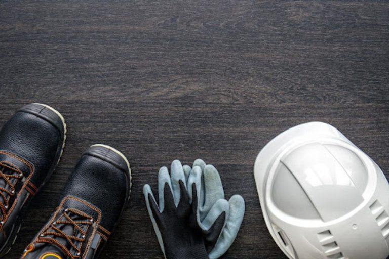 Esta imagem mostra itens de Equipamento de Proteção Individual (EPI) em uma superfície escura de madeira.