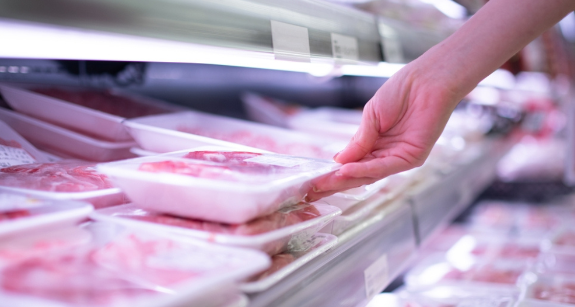 
A imagem é um close-up que ilustra o momento da compra de carne embalada em um supermercado.