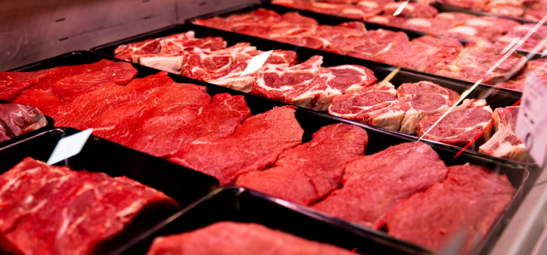 A imagem mostra uma vitrine refrigerada de um açougue ou supermercado, repleta de diversos cortes de carne fresca prontos para a venda.