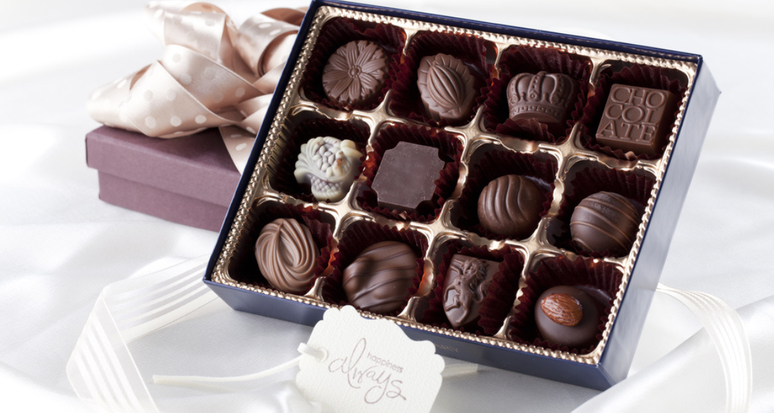 A imagem mostra uma caixa elegante de bombons finos em uma apresentação sofisticada, perfeita para presente.