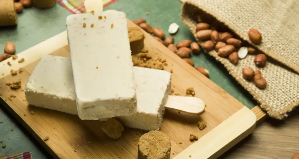 Imagem de sorvete de castanha de baru em uma tábua de madeira, com castanhas ao redor.