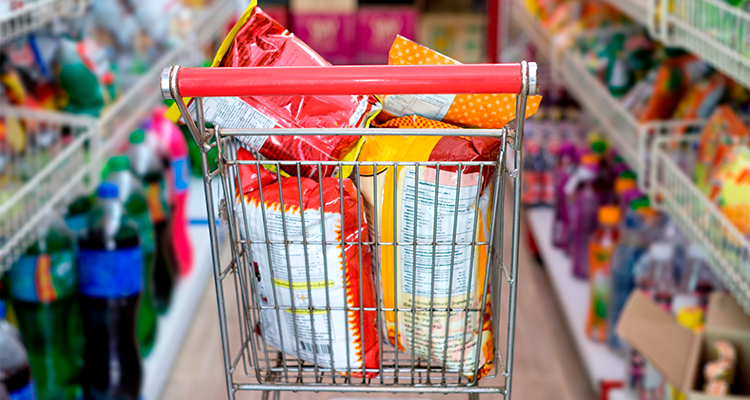 Alimentos ultraprocessados: carrinho de supermercado com dois pacotes de salgadinhos dentro.