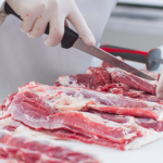 A imagem mostra uma cena de processamento de carne suina, provavelmente em um frigorífico, açougue ou ambiente de preparo de alimentos profissional.