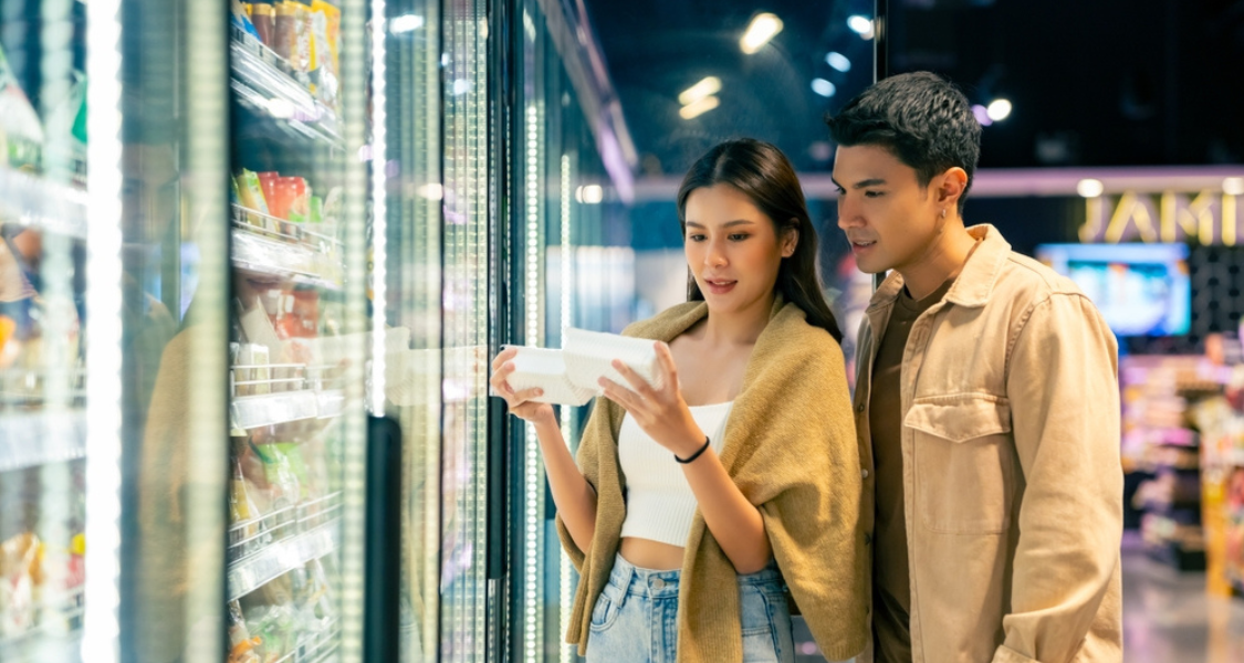 Esta imagem retrata um casal jovem em um momento de escolha consciente durante as compras em um supermercado.