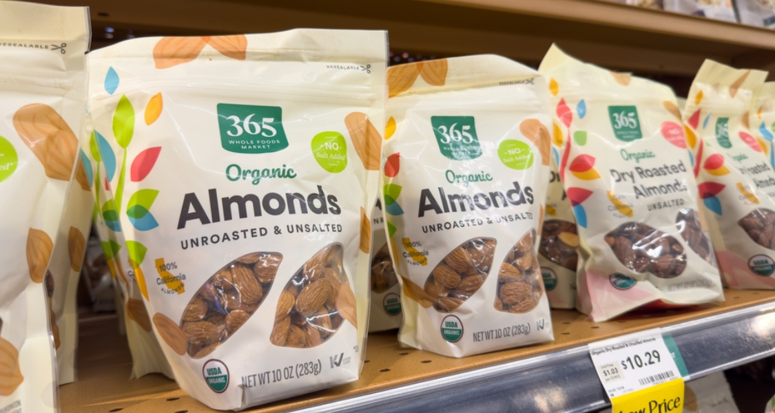 Esta imagem foca em pacotes de amêndoas organizados em uma prateleira de supermercado, destacando produtos de uma linha orgânica e natural.