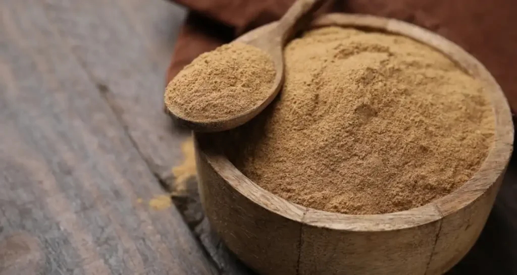Imagem de um pó de fibras alimentares dentro de uma tigela de madeira com uma colher.