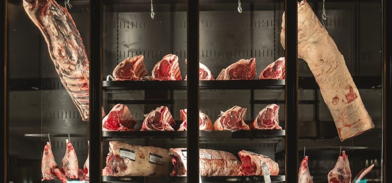 Exposição de cortes de carne em vitrine refrigerada, ideal para amantes de churrasco e culinária, destacando a variedade de carnes disponíveis.