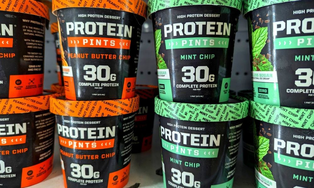 Potes de sorvete proteico (Protein Pints) expostos em uma prateleira de supermercado.