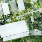 Imagem aérea mostrando uma usina de energia com equipamentos industriais e tubulações, cercada por árvores verdes, destacando a eficiência energética na indústria alimentícia.