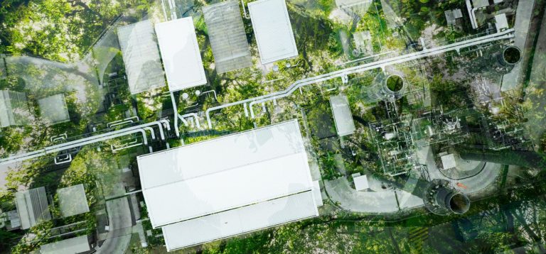 Imagem aérea mostrando uma usina de energia com equipamentos industriais e tubulações, cercada por árvores verdes, destacando a eficiência energética na indústria alimentícia.