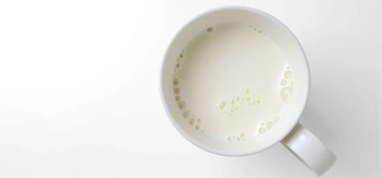 Tigela branca vista de cima com leite ou bebida láctea sobre fundo branco, ideal para descrever conteúdo relacionado a leite ou produtos lácteos. A imagem reflete sobre fermentação de precisão.