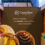 Exposição de diversas trufas artesanais de sabores variados na loja CacauShow, com destaque para trufas cremosas e coloridas.