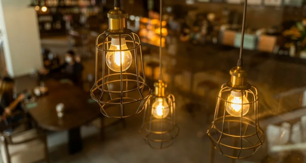 Detalhes de luminárias de pendente de ferro com lâmpadas incandescentes formando uma atmosfera acolhedora em um restaurante ou café à noite.
