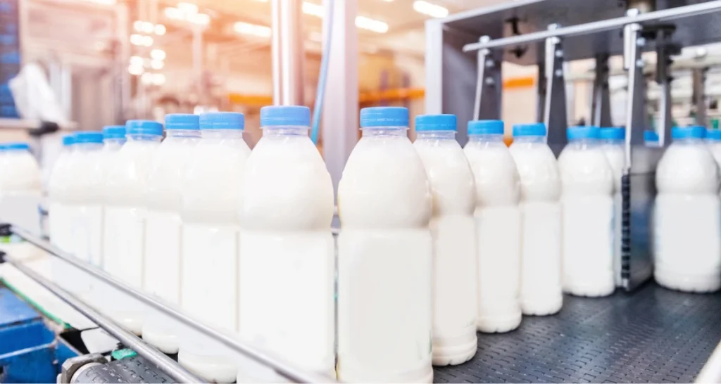 Produção de leite em garrafas em linha de montagem na indústria de laticínios, ambiente de fábrica com tecnologia avançada.