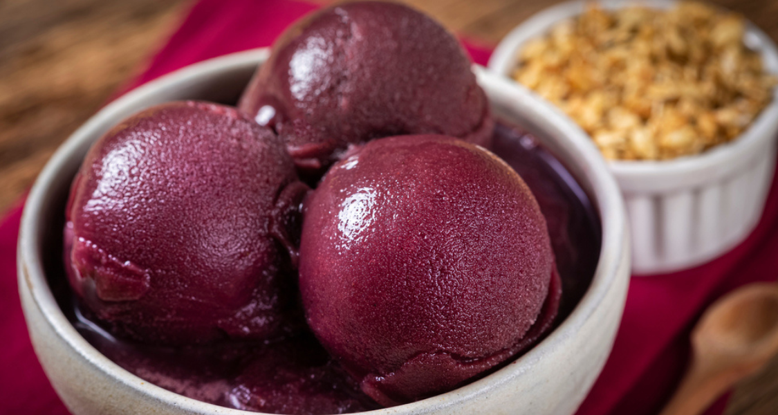 A imagem mostra um delicioso sorvete de açaí, servido em uma tigela de cerâmica.