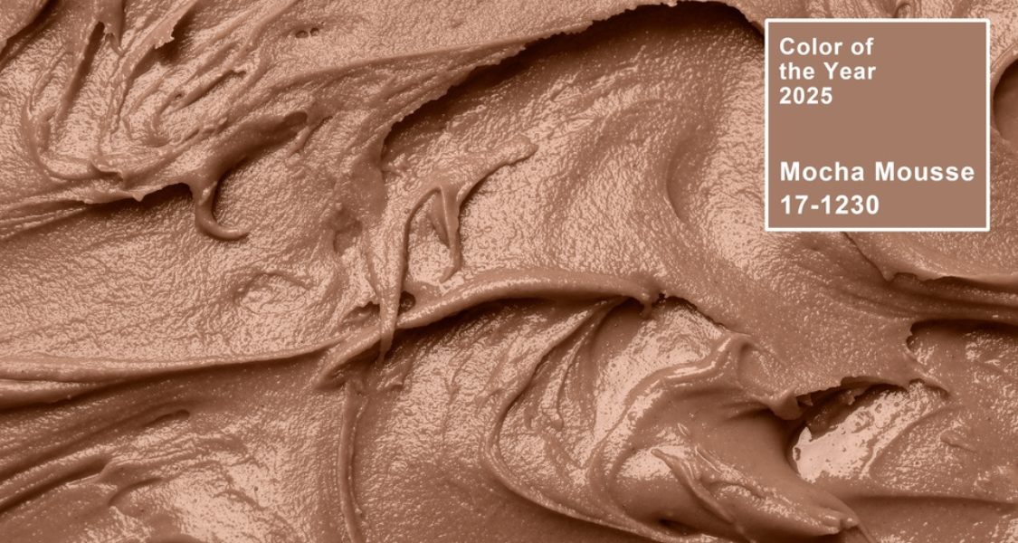 A imagem é um close-up que mostra a textura cremosa e espessa de uma substância que se assemelha a uma mousse, sorvete, ou cobertura de cor marrom-claro ou bege.