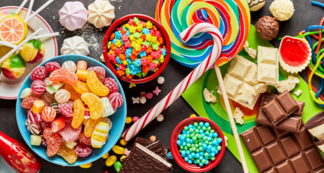 
Descrição da Imagem: Banquete de Doces e Sorvetes
Esta é uma imagem panorâmica e vibrante, tirada de cima (plano flat lay ou zenital), que mostra uma profusão de doces, guloseimas e sorvetes, dispostos em uma superfície escura. A composição é colorida, rica em texturas e centrada na indulgência.