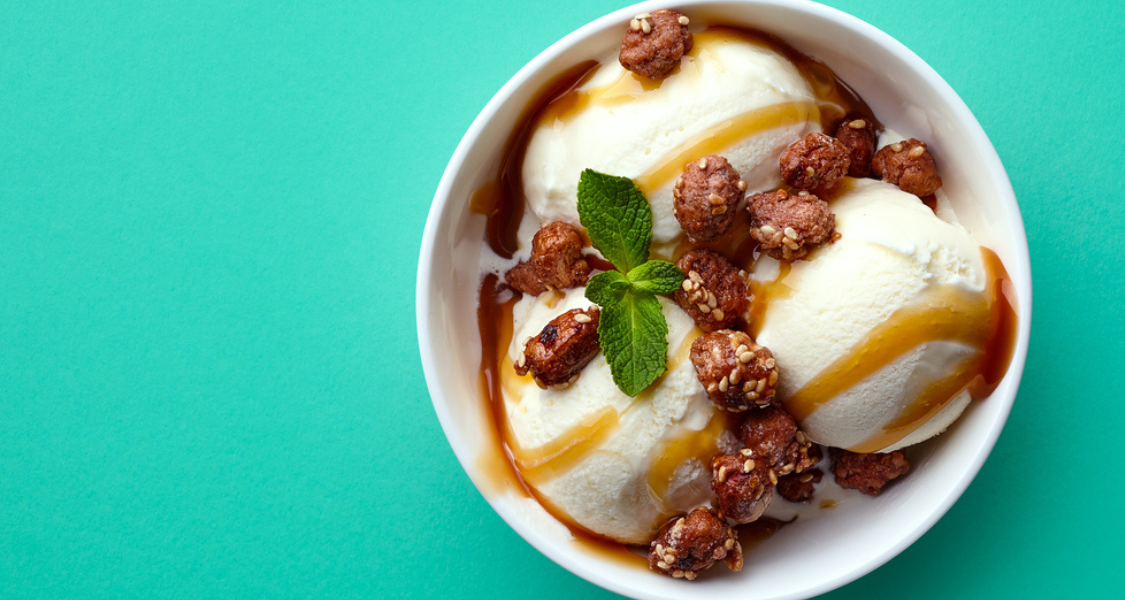 A imagem é uma fotografia vibrante e minimalista, tirada de cima (plano flat lay ou zenital), que foca em uma taça de sorvete com um contraste forte entre o alimento cremoso e o fundo colorido.