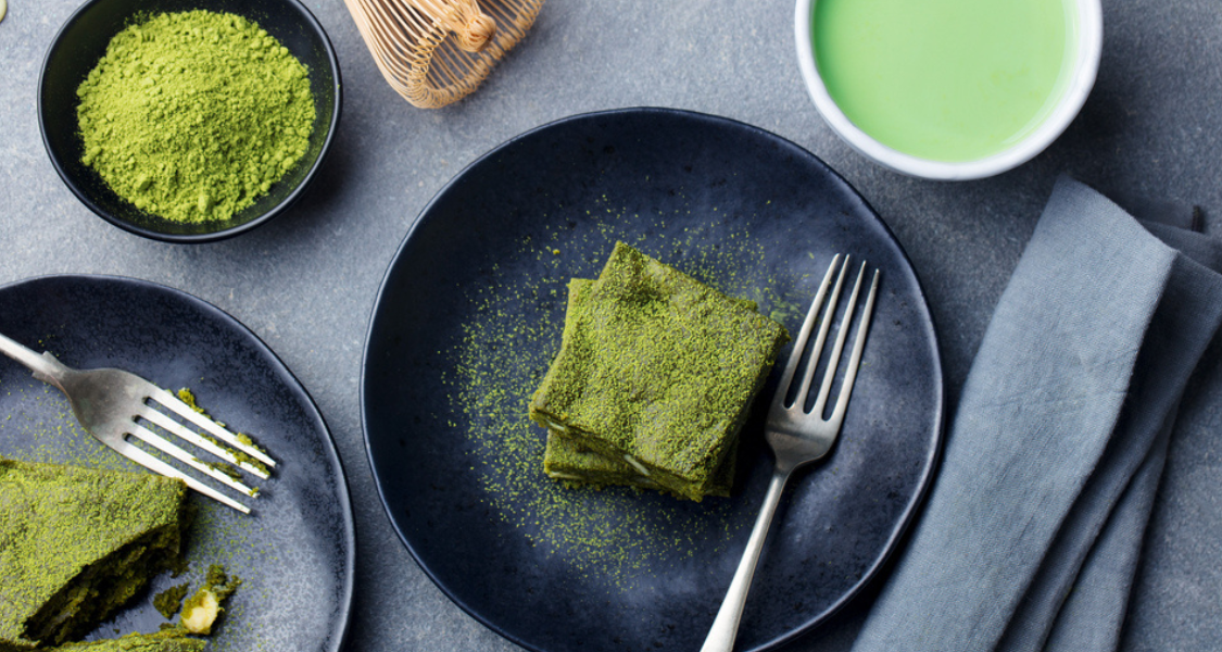 A imagem mostra uma composição elegante de sobremesas e bebida feitas com matcha (chá verde em pó).