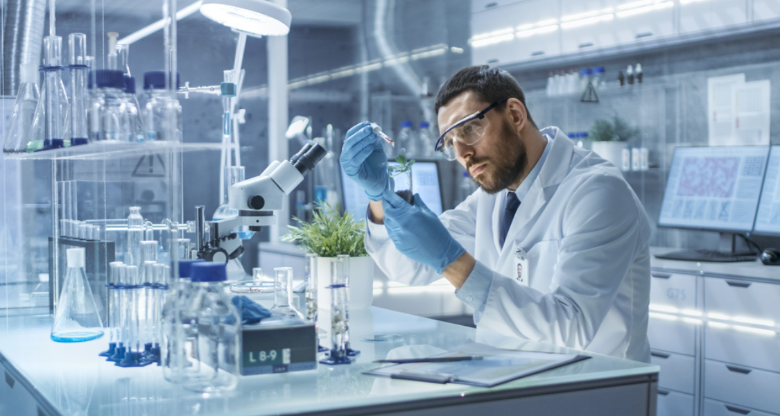 A imagem mostra um cenário de laboratório moderno e bem iluminado, focado em um cientista realizando uma análise.