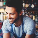 Homem sorridente com avental em um bar, sobreposto por gráficos e elementos digitais que representam dados e tecnologia, simbolizando o uso de informações do consumidor no setor de foodservice.
