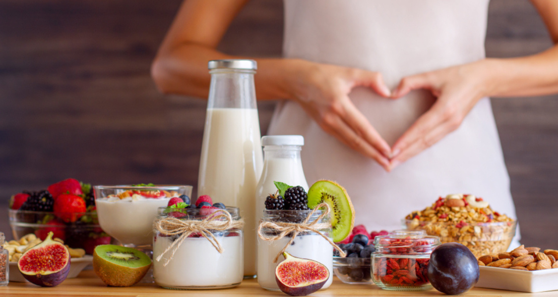 A imagem retrata uma cena focada em alimentação saudável, digestão e a saúde intestinal, com um forte apelo visual a produtos lácteos, frutas e alimentos integrais.