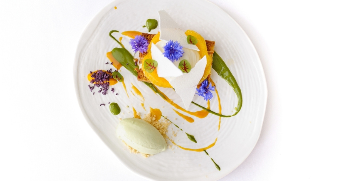 imagem apresenta uma sobremesa de alta confeitaria vista de cima, exemplificando a fusão entre técnica gastronômica e arte visual.