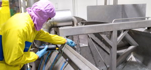 A imagem mostra uma mulher em um corredor de supermercado, concentrada em examinar e comprar bebidas refrigeradas.