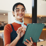A imagem captura uma mulher jovem em um ambiente profissional e moderno, possivelmente um café, restaurante ou recepção.