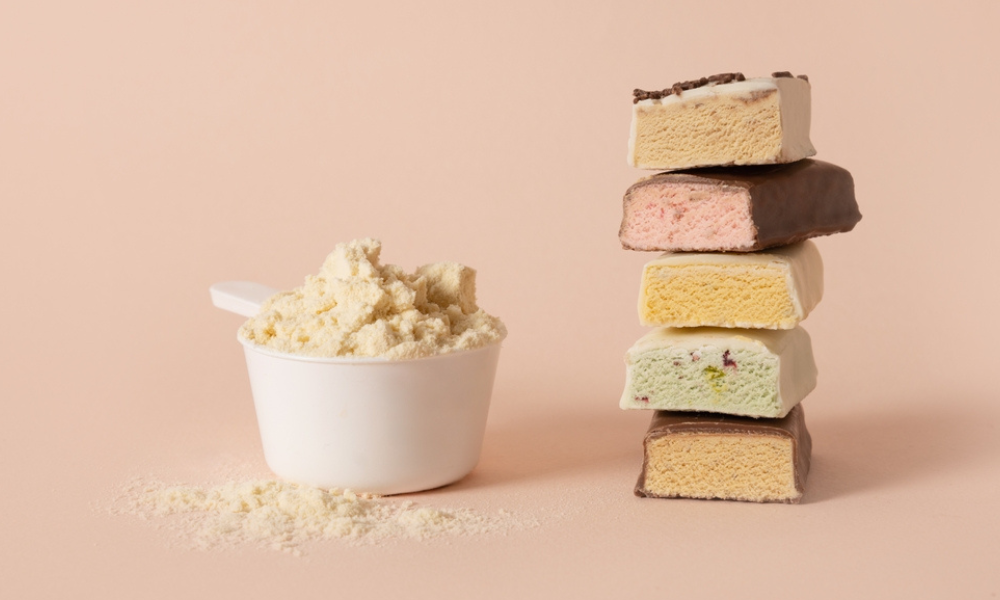 A imagem apresenta uma composição visual relacionada à suplementação proteica e nutrição esportiva, com foco em suplementos em pó e barras proteicas.