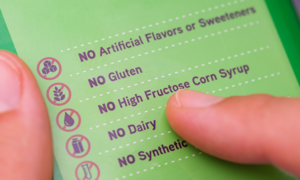 Esta imagem mostra um close-up de um rótulo de produto (provavelmente alimentício ou suplemento) com foco em suas certificações e ausência de determinados ingredientes.