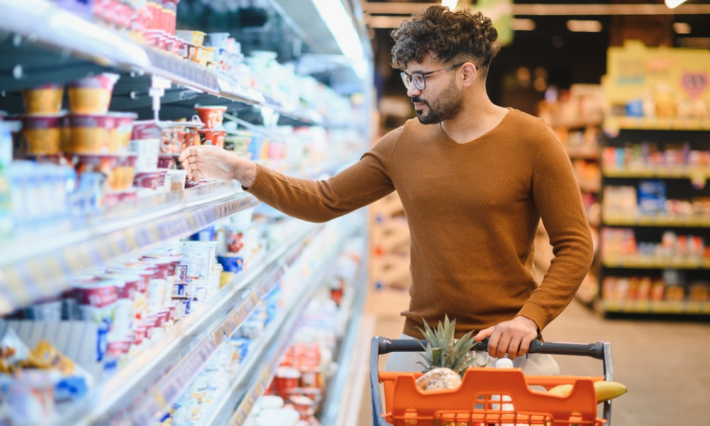 Esta imagem retrata uma cena comum de consumo consciente e rotina saudável em um ambiente de supermercado.