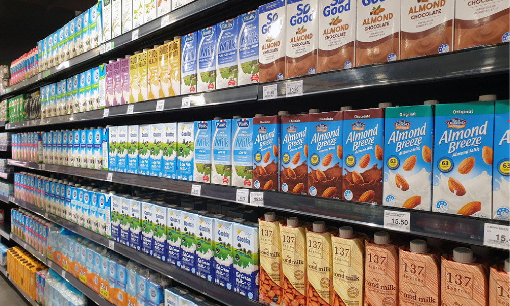 Prateleiras de um supermercado repletas de diversas marcas de leite e bebidas vegetais (como leite de amêndoas e chocolate). É possível ver marcas conhecidas como Almond Breeze, So Good e 137 Degrees.