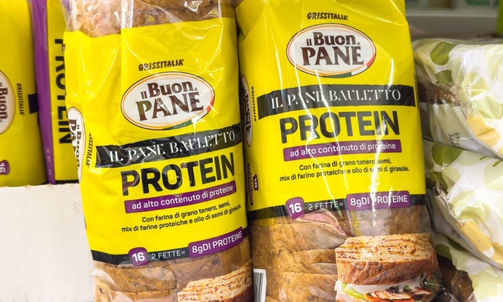 Pacotes de pão de forma da marca "Il Buon Pane Protein" em uma prateleira de supermercado, destacando o alto teor de proteínas.