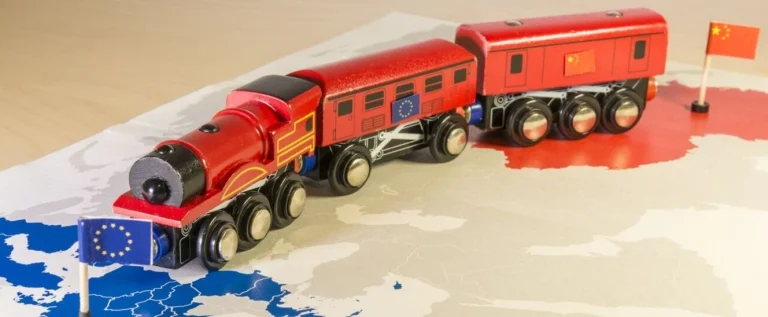 trem de brinquedo vermelho sobre um mapa, saindo da china e indo em direção à união europeia, simbolizando a nova rota da seda