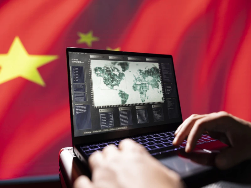 pessoa mexendo em notebook com a nova rota da seda na tela, e a bandeira da china ao fundo