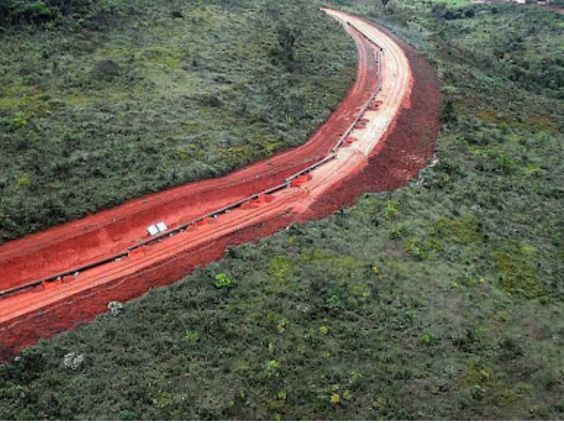 A imagem mostra uma estrutura típica do modal dutoviário, que consiste em um oleoduto ou gasoduto atravessando uma região de vegetação nativa. A via escavada e avermelhada, cercada por vegetação, indica a instalação de dutos subterrâneos ou semi-enterrados para o transporte de fluidos, como petróleo, gás natural ou outros líquidos industriais.