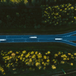 Essa imagem oferece uma vista aérea deslumbrante de uma rodovia cortando uma densa floresta, destacando o contraste entre a infraestrutura humana e a natureza circundante.