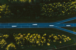 Essa imagem oferece uma vista aérea deslumbrante de uma rodovia cortando uma densa floresta, destacando o contraste entre a infraestrutura humana e a natureza circundante.