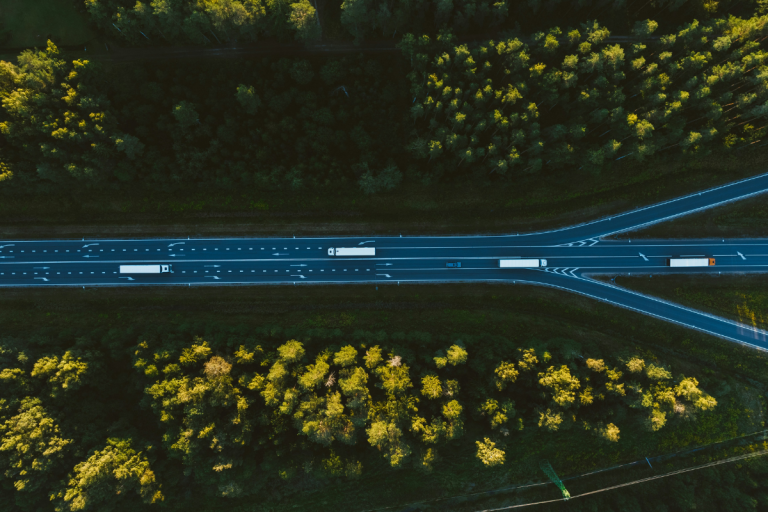 Essa imagem oferece uma vista aérea deslumbrante de uma rodovia cortando uma densa floresta, destacando o contraste entre a infraestrutura humana e a natureza circundante.