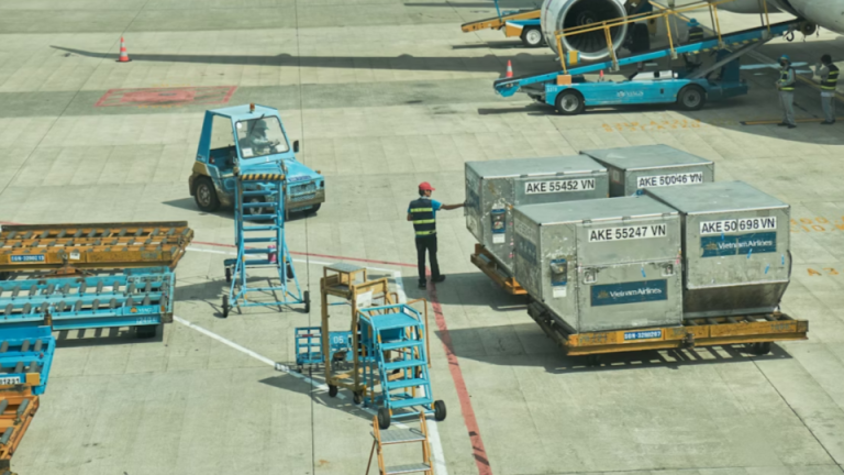 Esta imagem captura a movimentação logística no pátio de um aeroporto, focando no carregamento ou descarregamento de carga de uma aeronave.