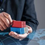 Empresário segurando contêineres de transporte contra o mapa do comércio mundial. Comércio global, logística e comércio. Simbolizar cadeias de fornecimento internacionais, exportações, importações, e a expansão dos mercados globais.