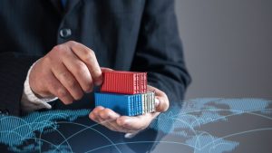 Empresário segurando contêineres de transporte contra o mapa do comércio mundial. Comércio global, logística e comércio. Simbolizar cadeias de fornecimento internacionais, exportações, importações, e a expansão dos mercados globais.