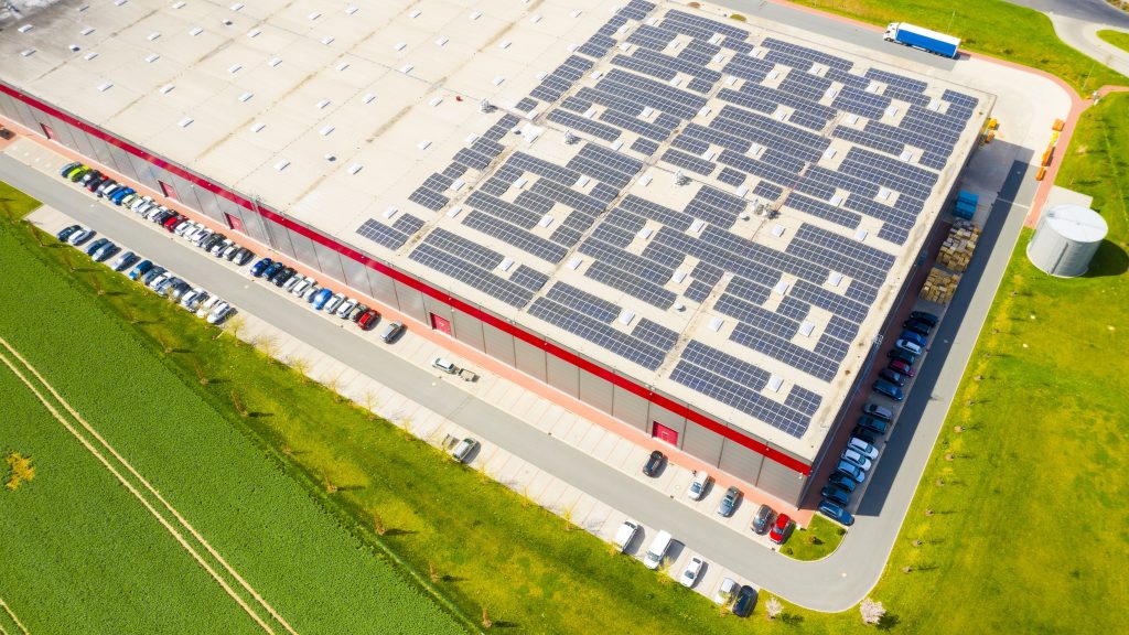 Indústria com baixa pegada de carbono. Galpões industriais com painéis solares no telhado. Parque tecnológico e fábricas vistos de cima.