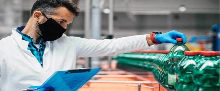 funcionário de jaleco, luva e máscara fazendo o controle de qualidade na indústria do plástico