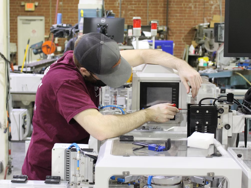 A imagem mostra um técnico ou engenheiro concentrado em trabalhar com o painel de controle de um equipamento industrial.